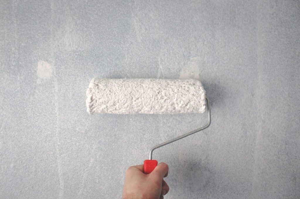 Rodillo pintando la pared de una vivienda en una reforma económica