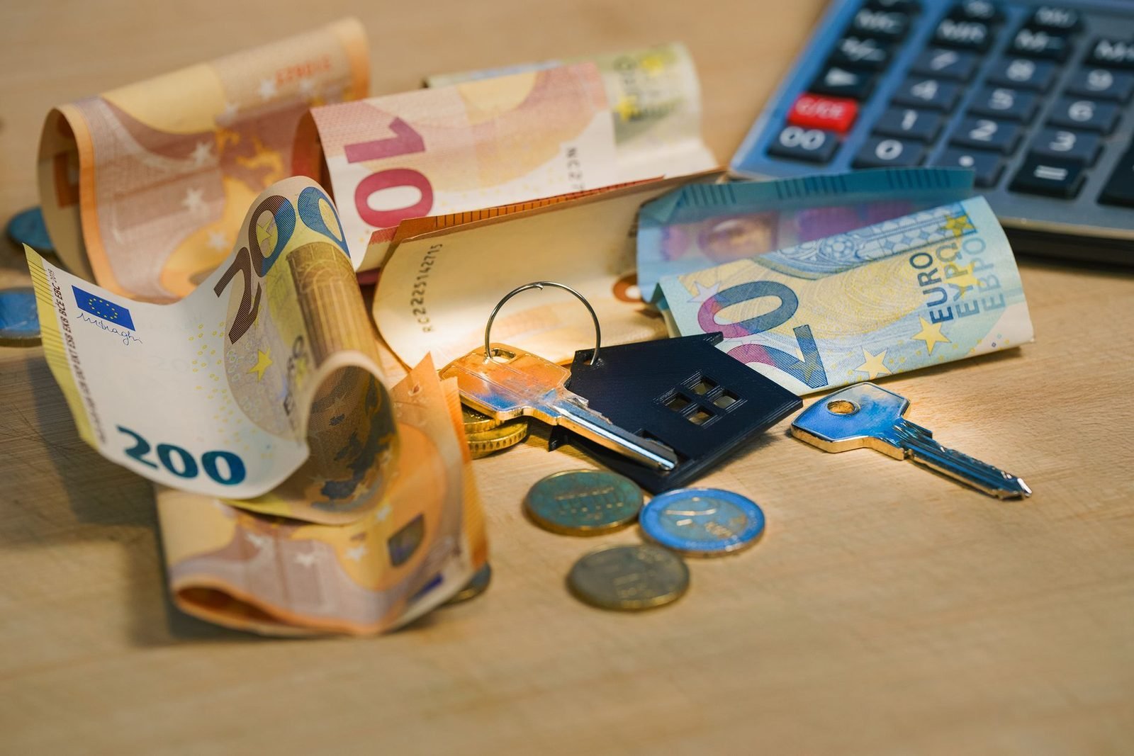 Billetes, monedas y llaves junto a la calculadora de gastos de compra